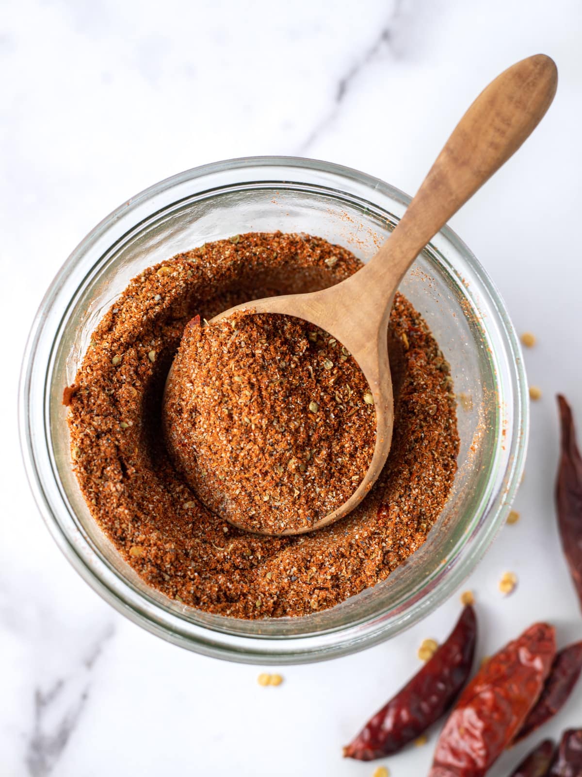 Jar filled with homemade taco seasoning and a large wooden spoon on top.