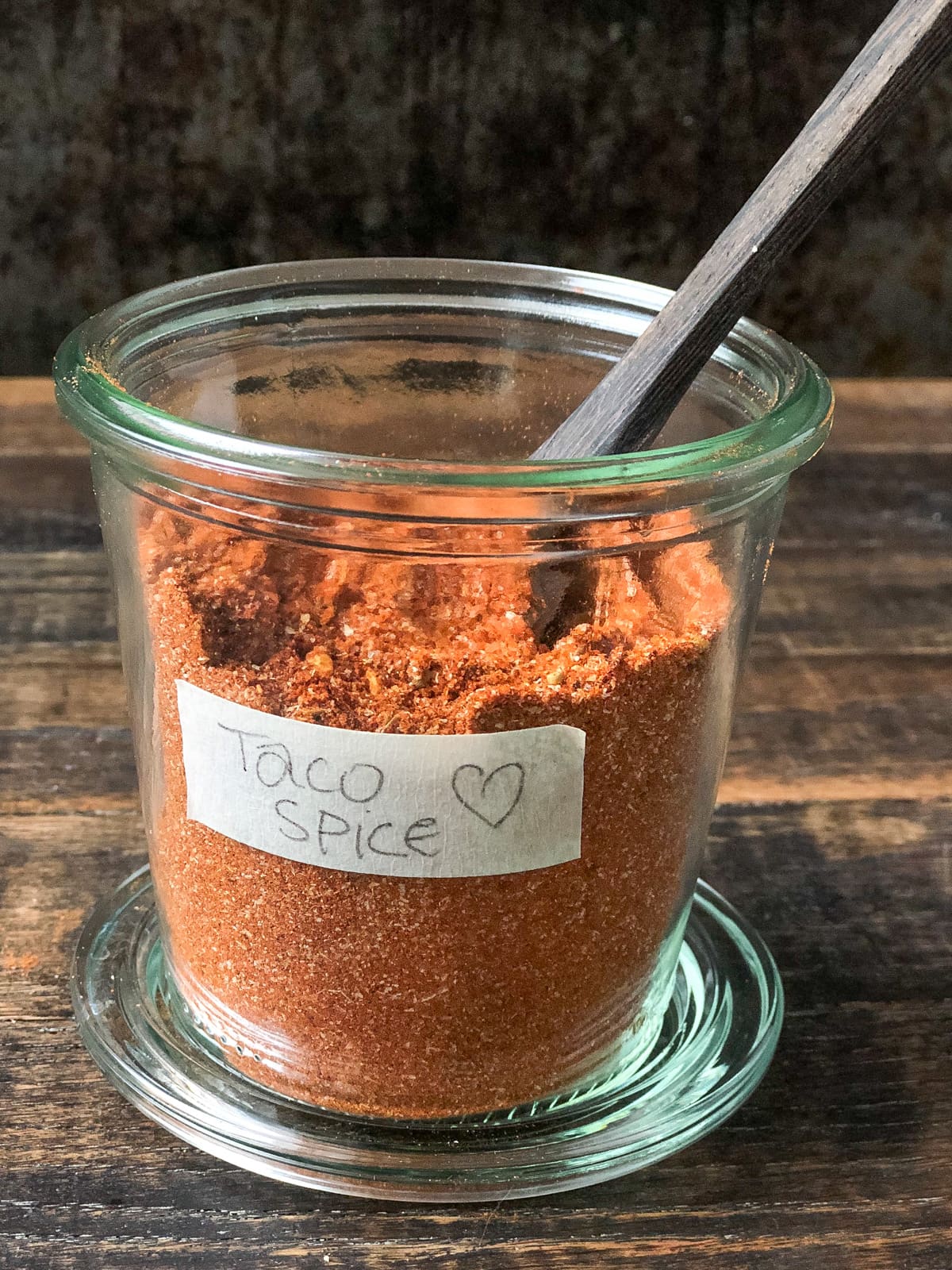 Jar full of homemade taco seasoning with a serving spoon.