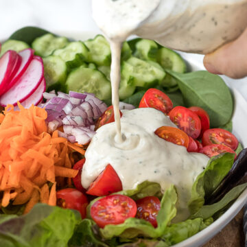 Ranch dressing pouring onto side salad.