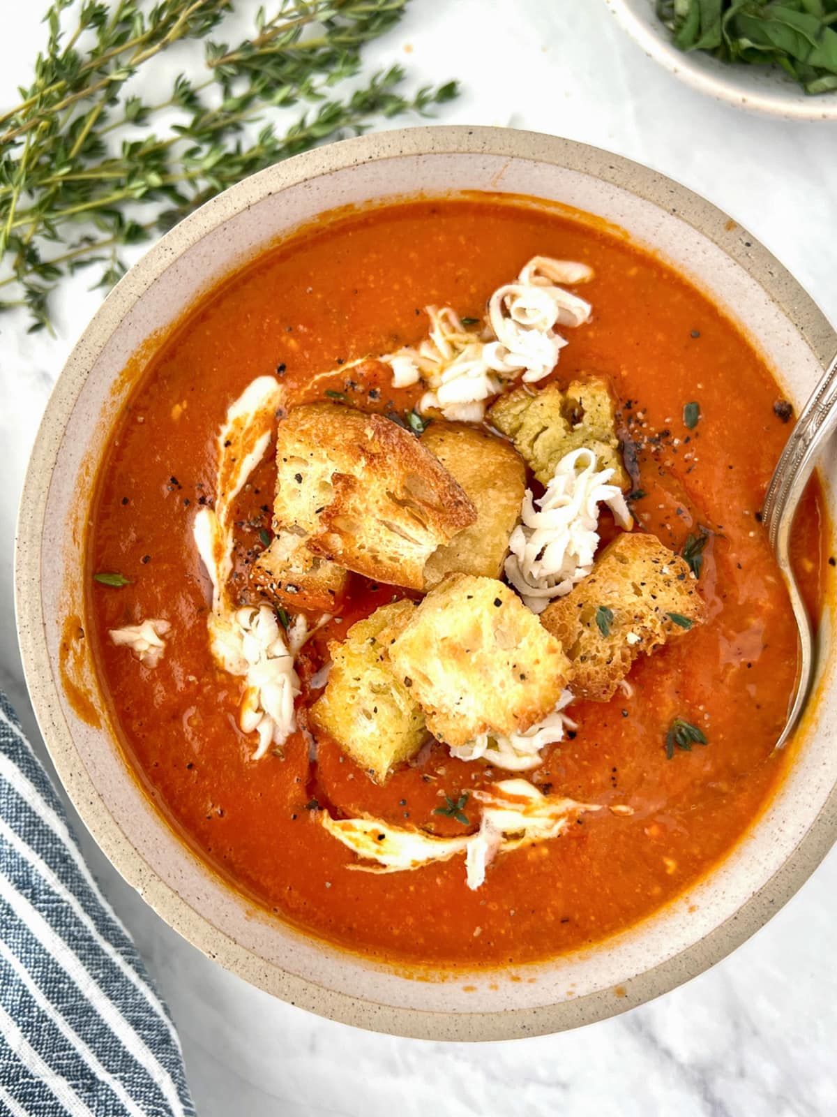 Bowl of tomato soup topped with croutons and shredded cheese.