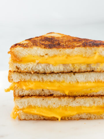 Stack of grilled cheese sandwich on a white counter top.