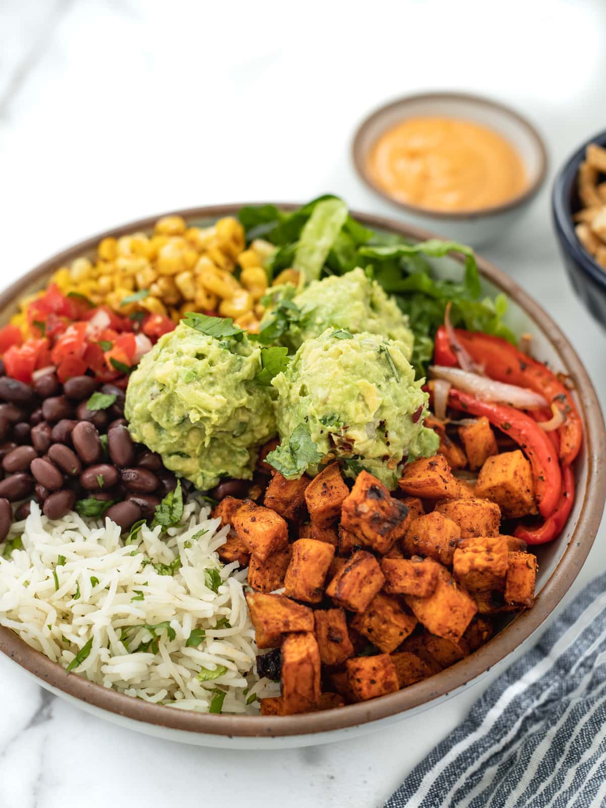 Sweet potato and black bean burrito bowl topped with guacamole and charred corn.