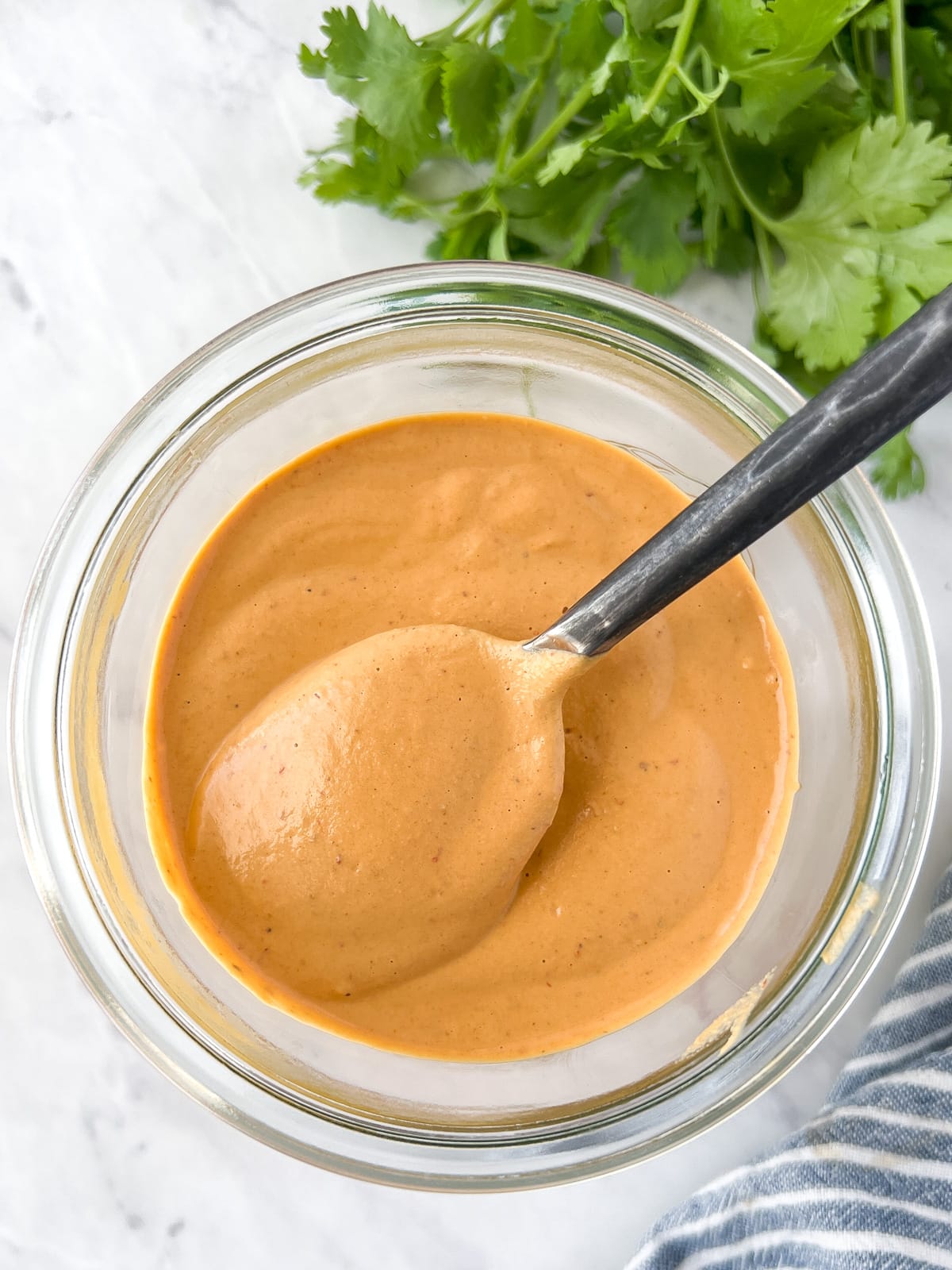 Chipotle sauce in a glass jar with a spoonful being lifted out.