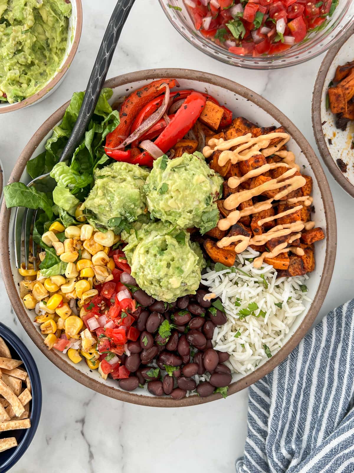 Burrito bowl with black beans, sweet potatoes, corn and balls of guacamole served on rice.