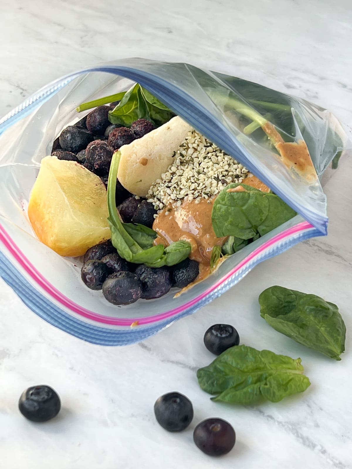 Frozen bananas, blueberries, fresh spinach and hemp hearts in a ziplock bag.