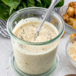 Vegan caesar dressing in a jar with a spoon for serving.