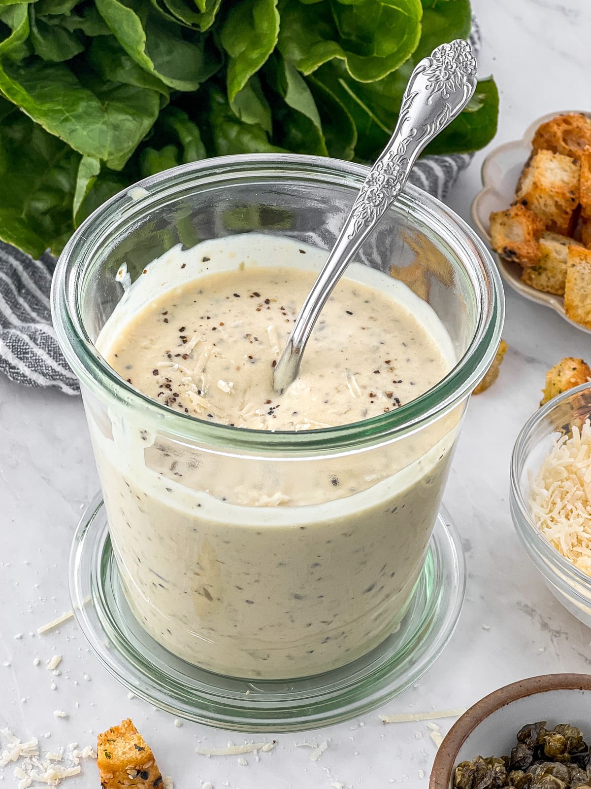 Vegan caesar dressing in a jar with a spoon for serving.