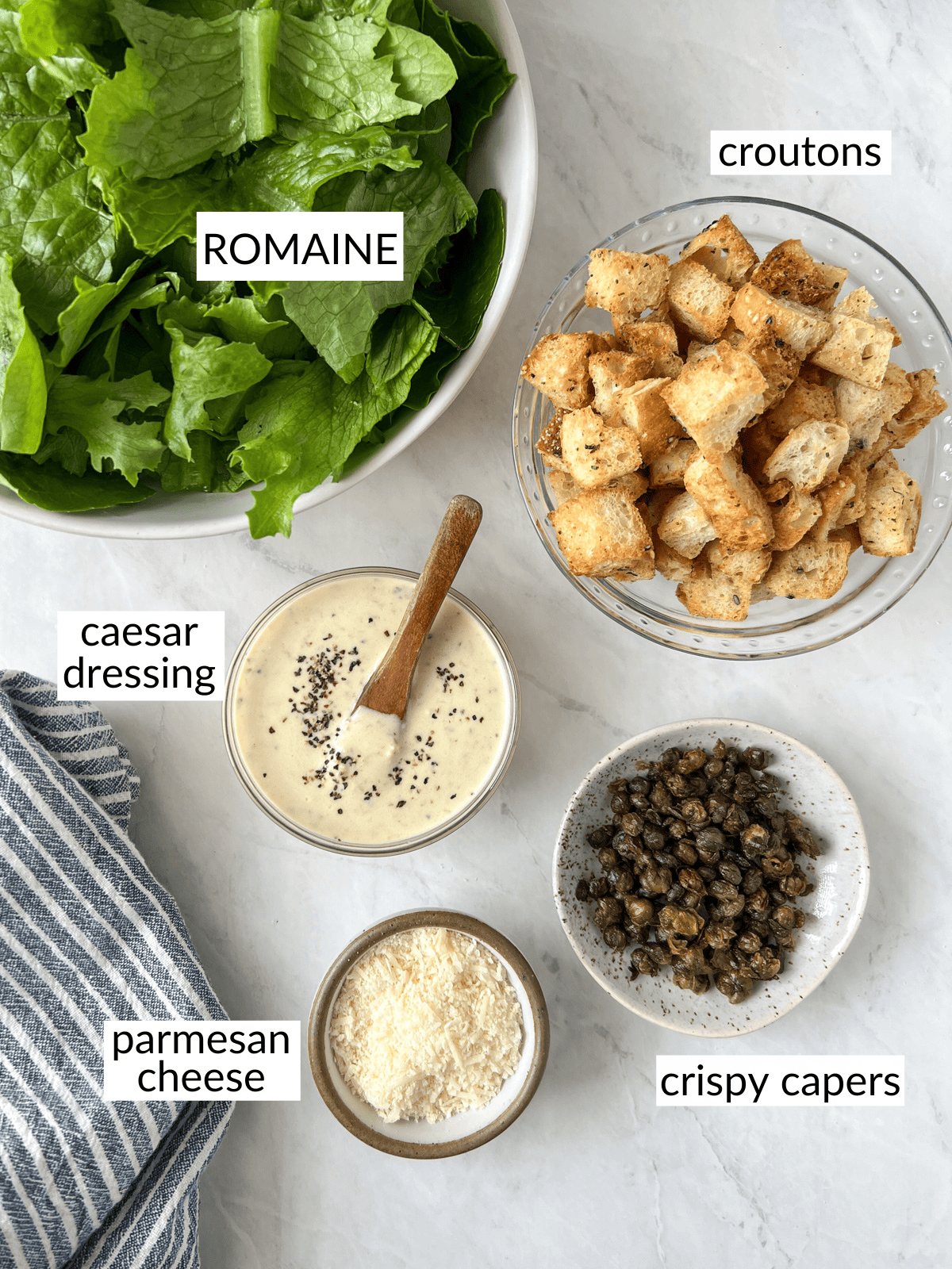 Ingredients to make a dairy free caesar salad set out in bowls.