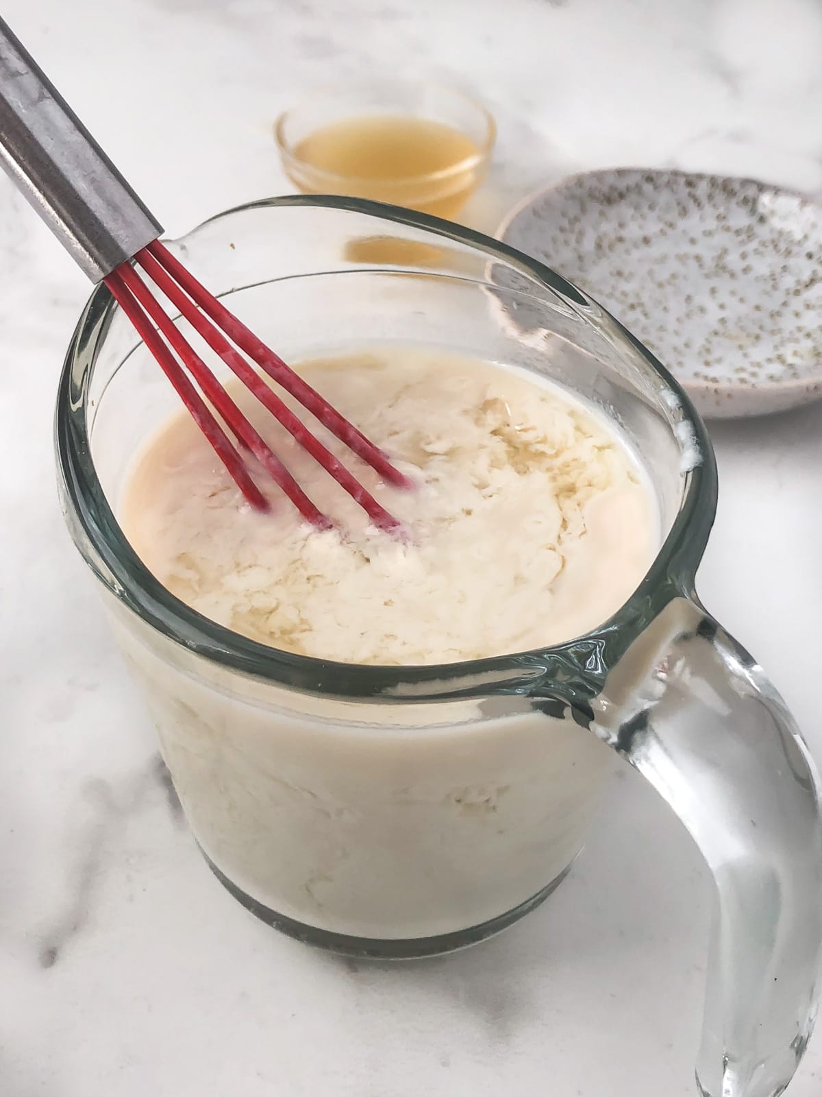 Homemade vegan buttermilk being whisked in a large measuring cup.