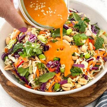 Japanese Carrot Ginger dressing being poured over Asian slaw.