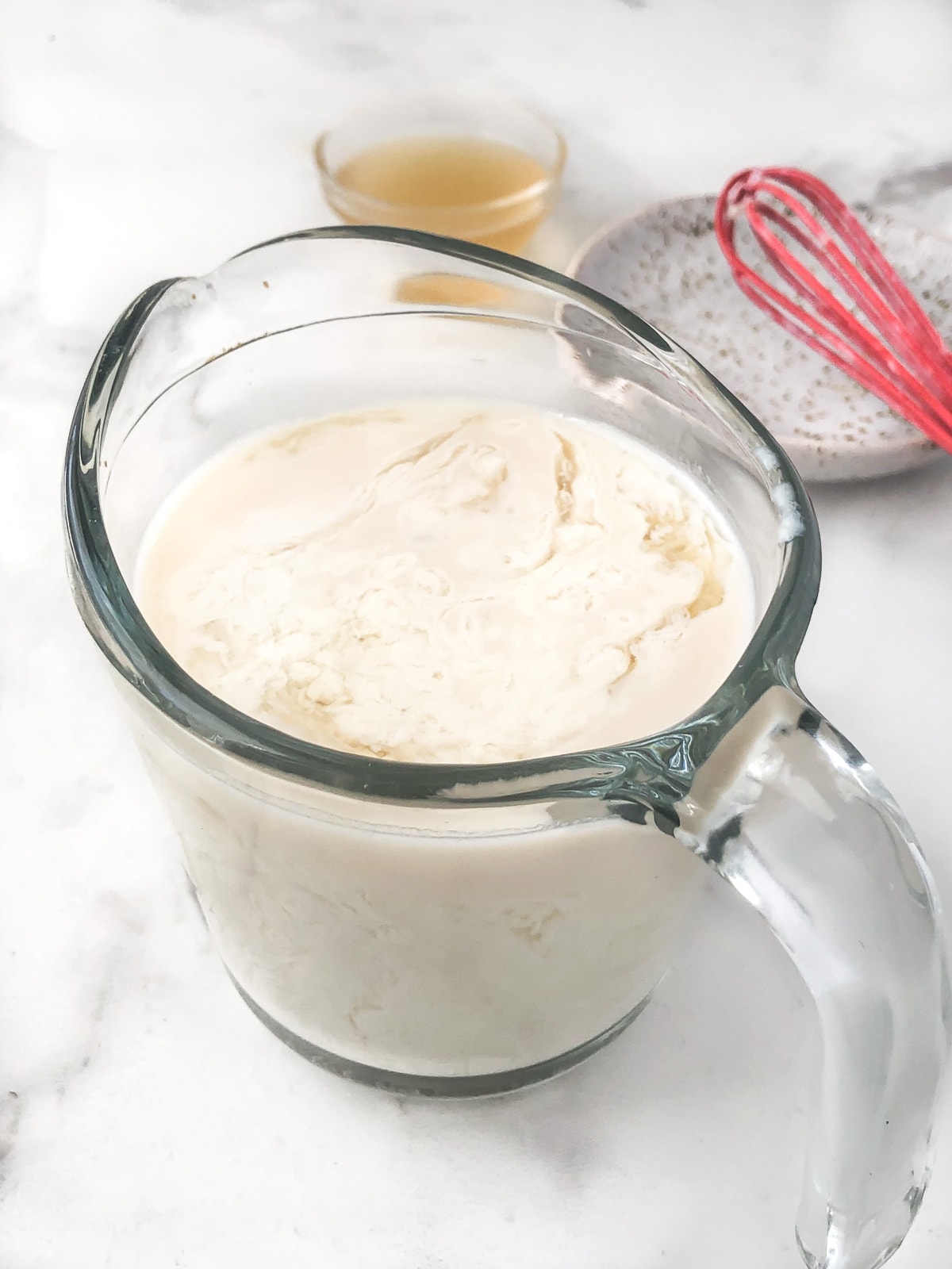 Measuring cup full of dairy free buttermilk curdling.