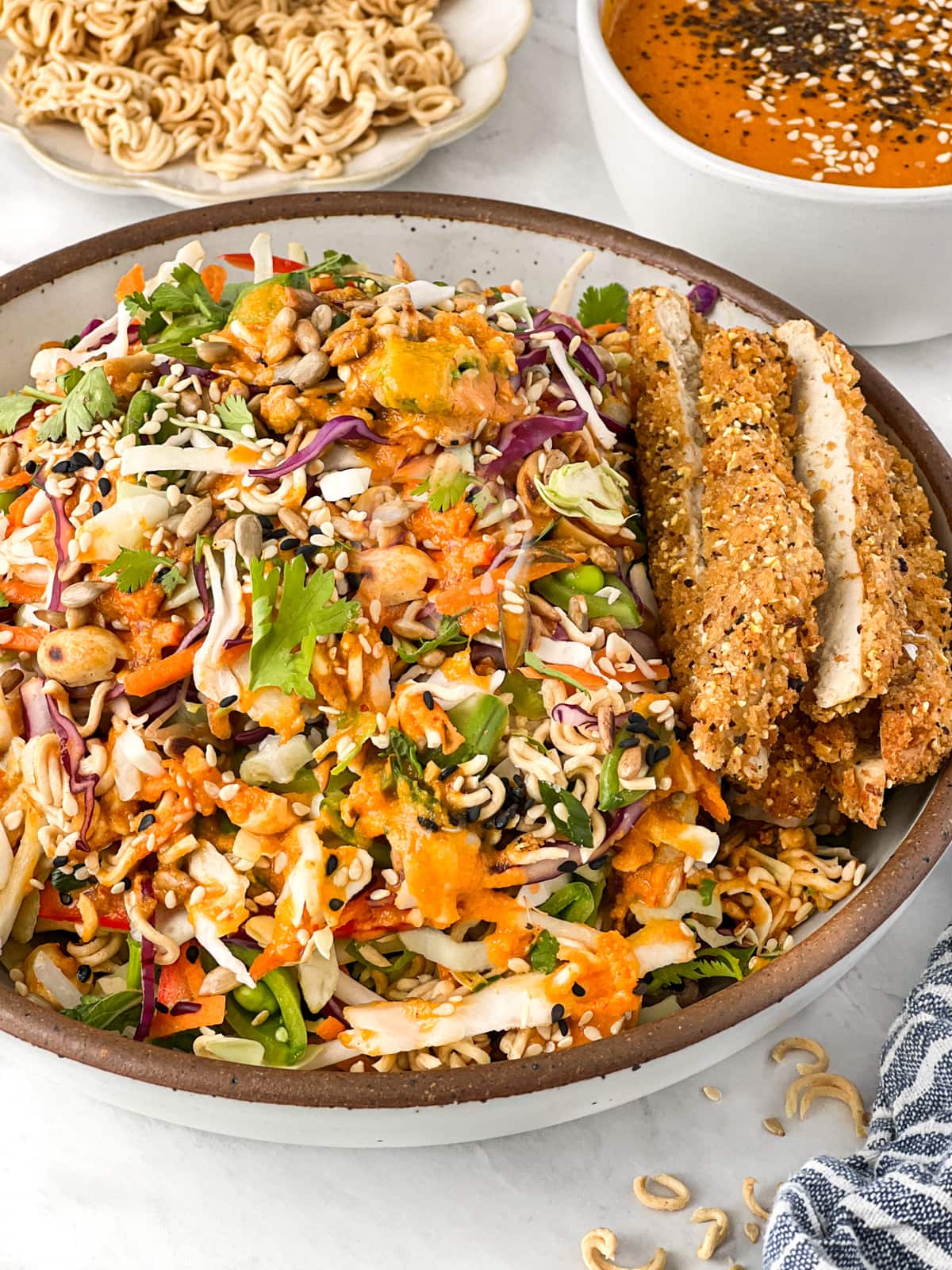 Bowlful of Oriental cabbage slaw topped with vegan chicken and ramen noodles.