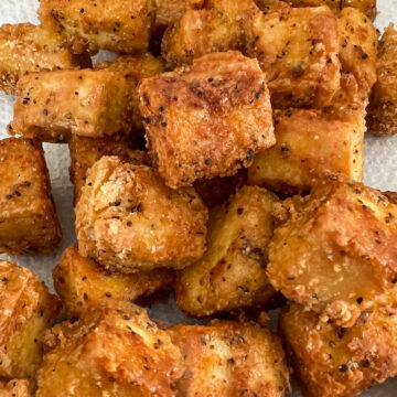 Freshly pan fried crispy tofu draining on a paper towel.