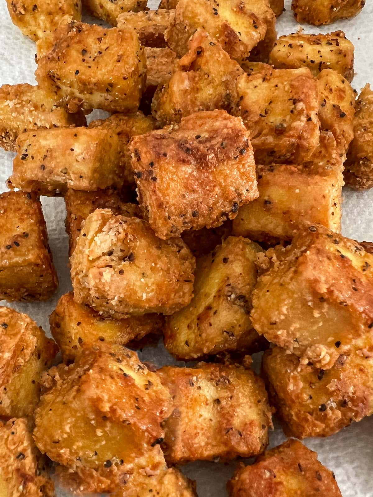 Freshly pan fried crispy tofu draining on a paper towel.