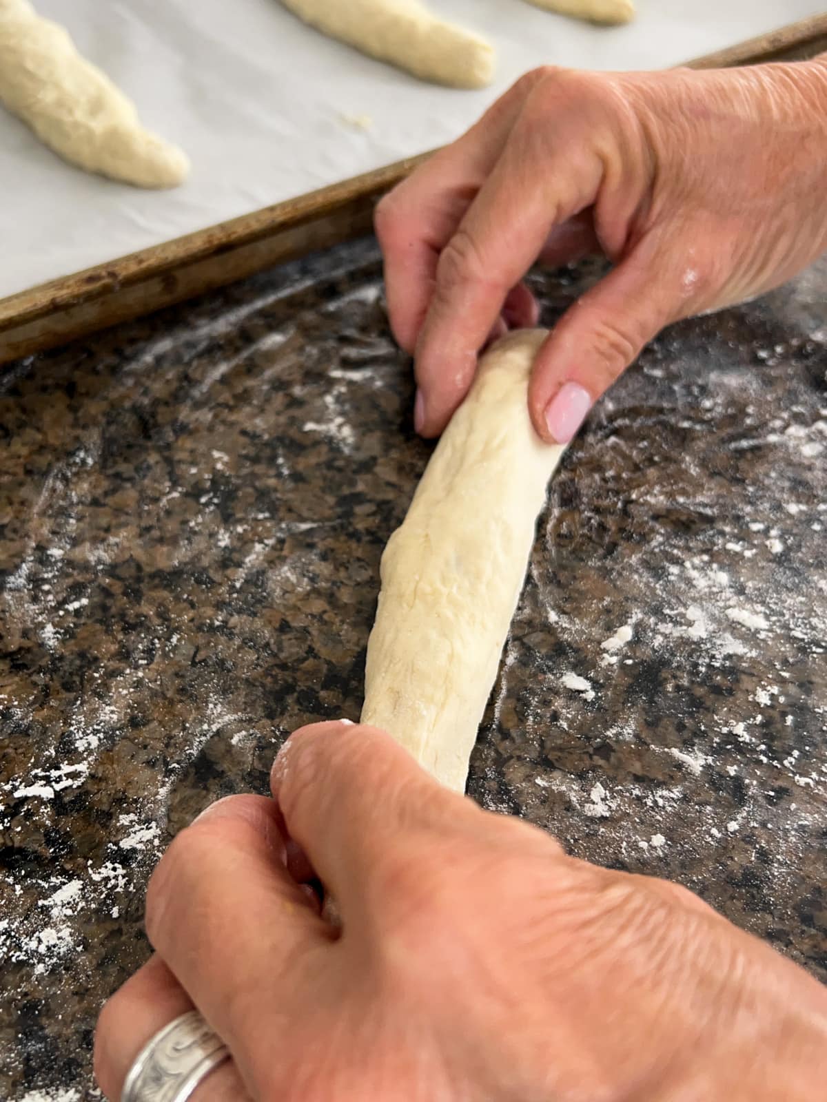 Piece of dough being rolled into a log to make breadsticks.