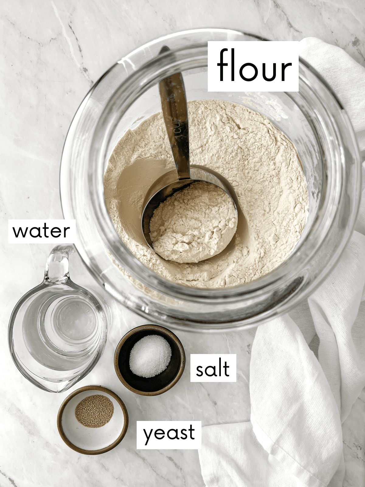 Flour, salt, water, and yeast measured into bowls to make peasant bread.