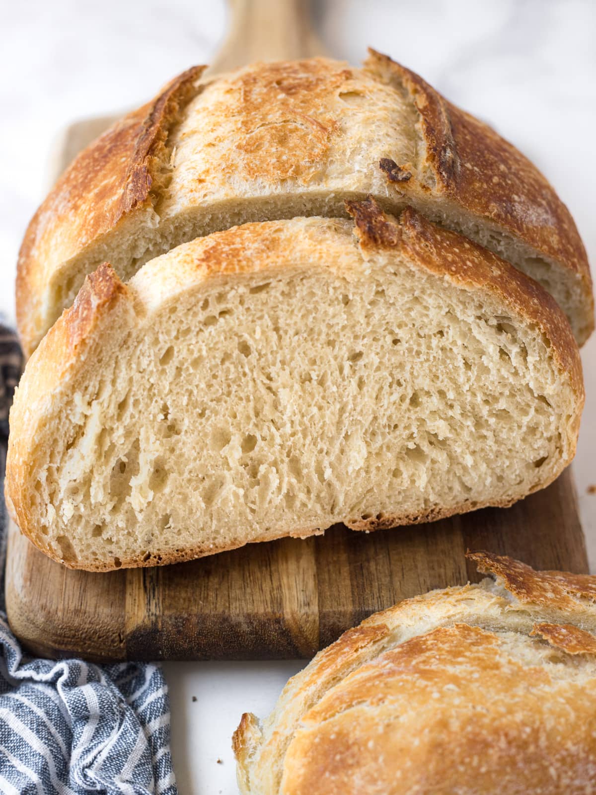 Freshly baked loaf of homemade bread on a cutting board with a few slices cut off.