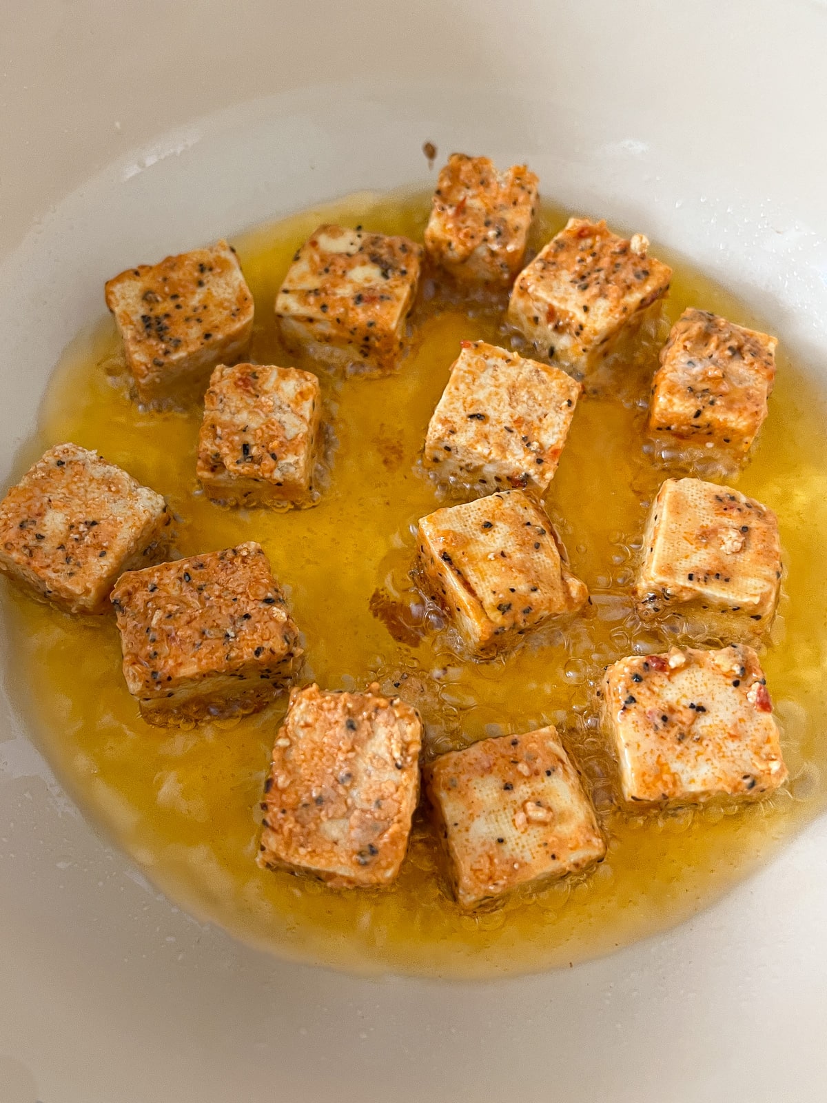 Seasoned tofu cubes being pan fried until brow and crispy.