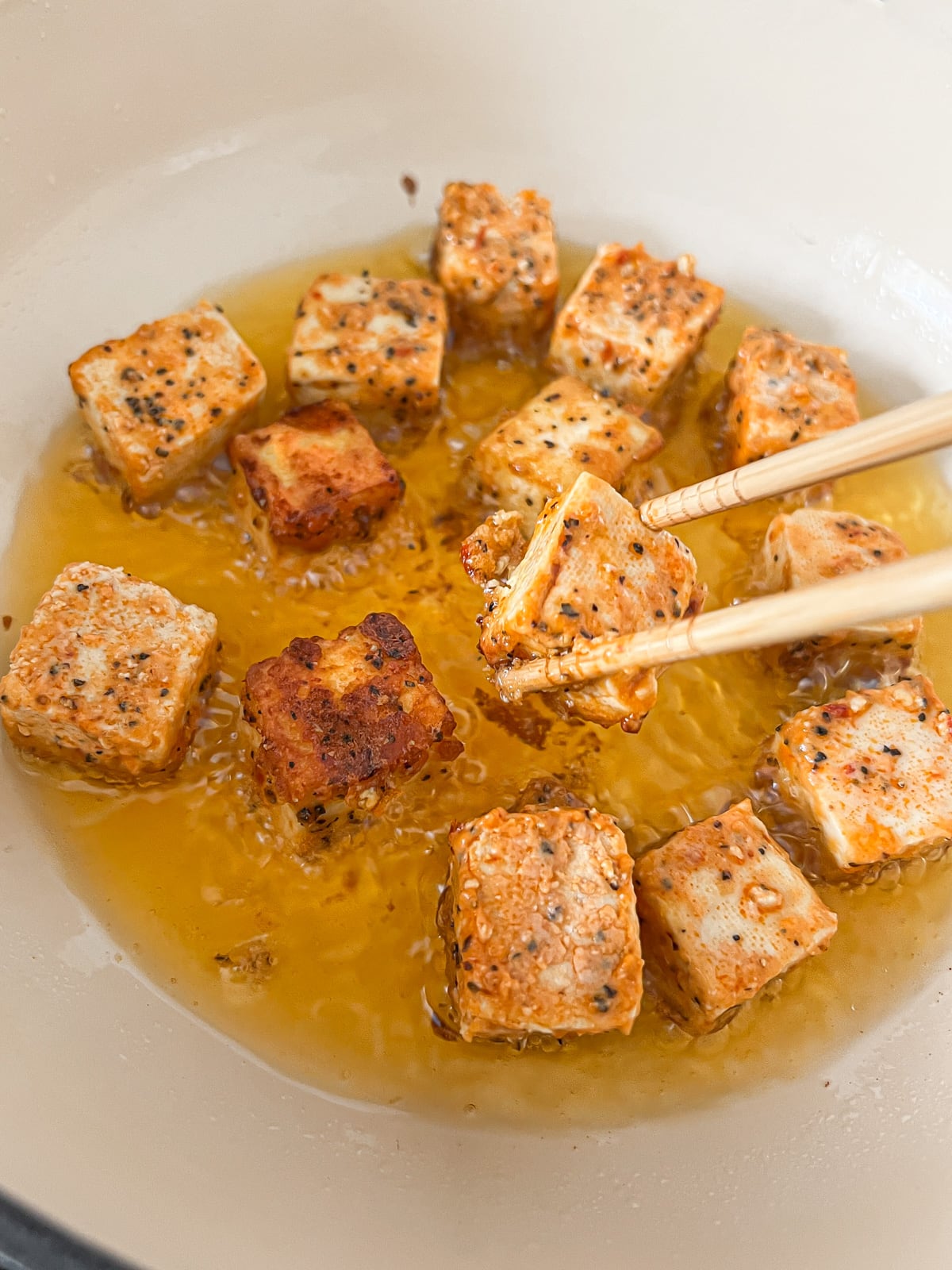 Tofu cubes frying in a hot pan.