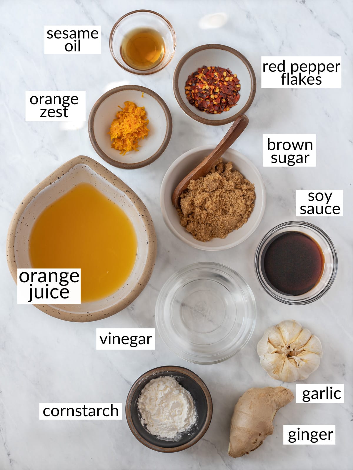 Ingredients to make orange sauce in individual bowls on counter top.
