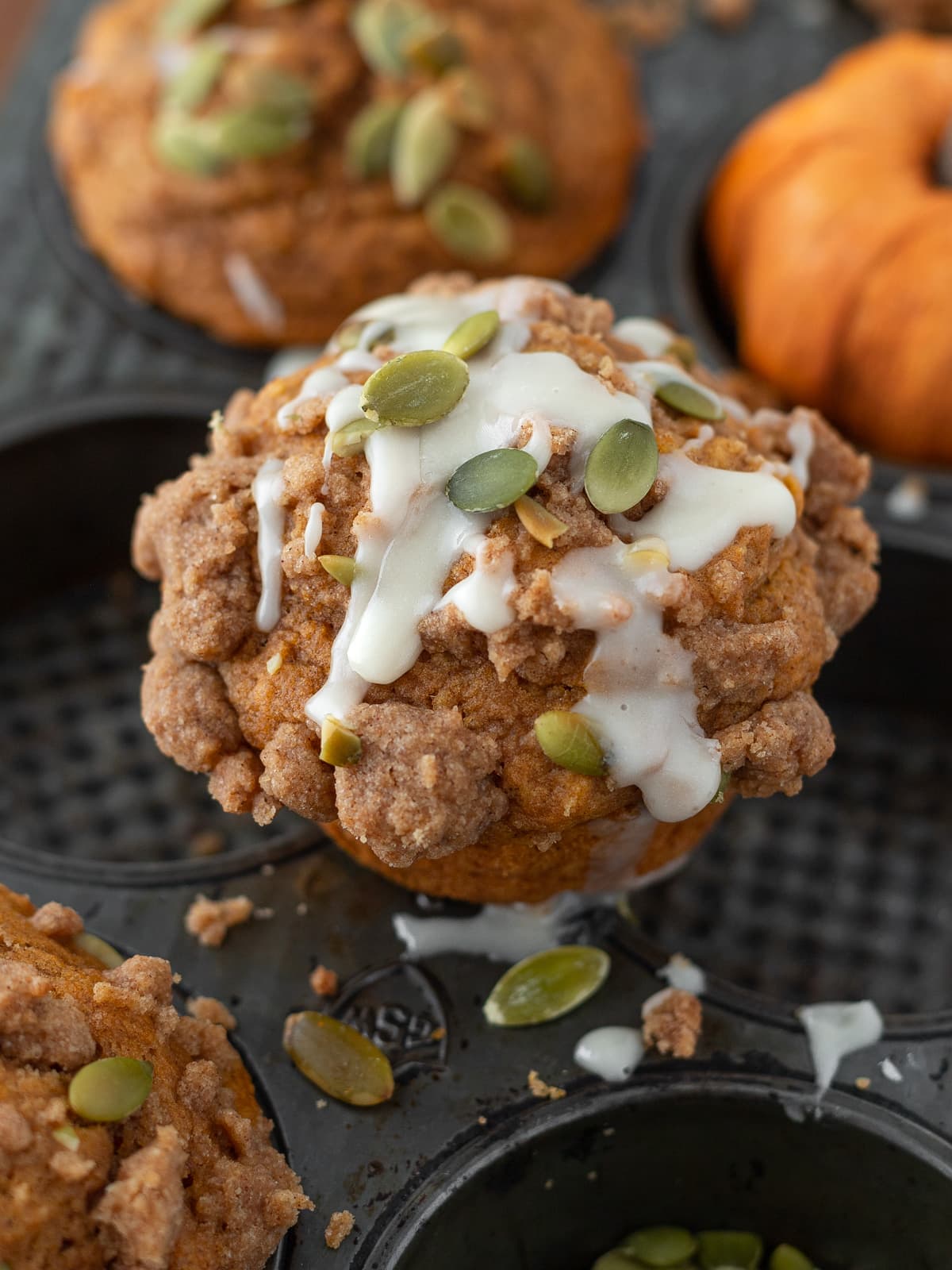 Pumpkin spice muffin drizzled with maple cinnamon frosting topped with pumpkin seeds.