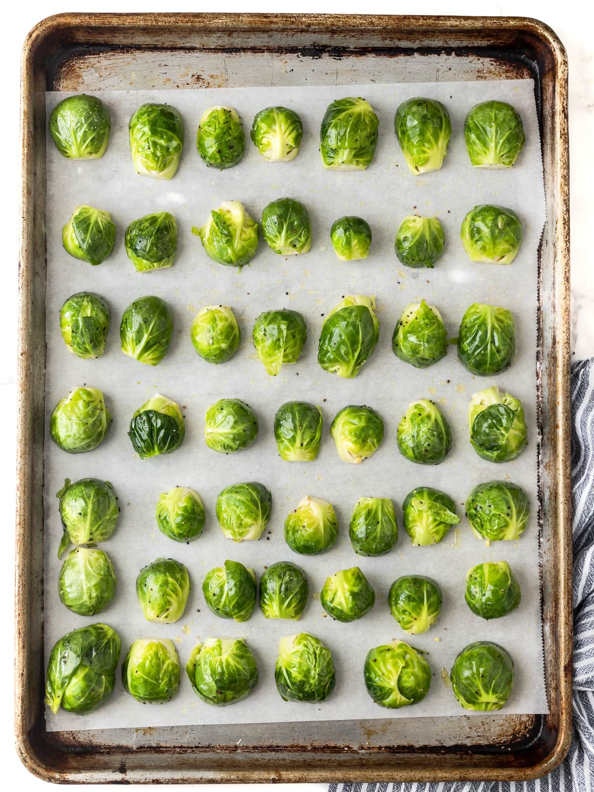 Brussels sprout halves lined up on a baking sheet.