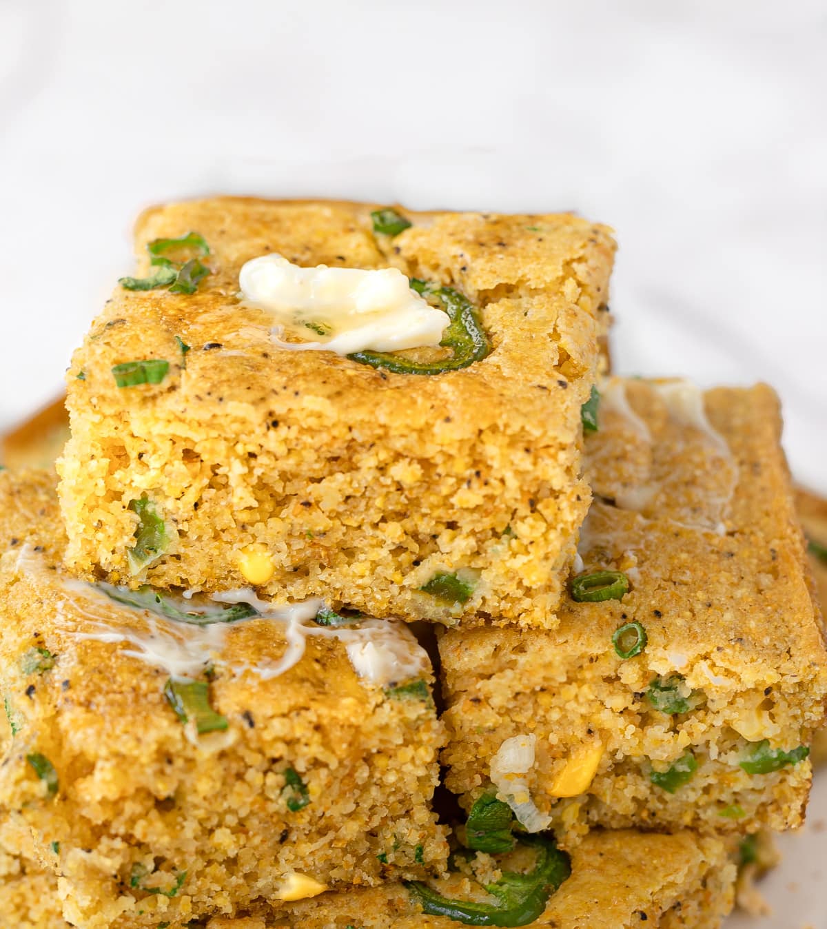 Stack of sliced cornbread topped with jalapenos and green onions.