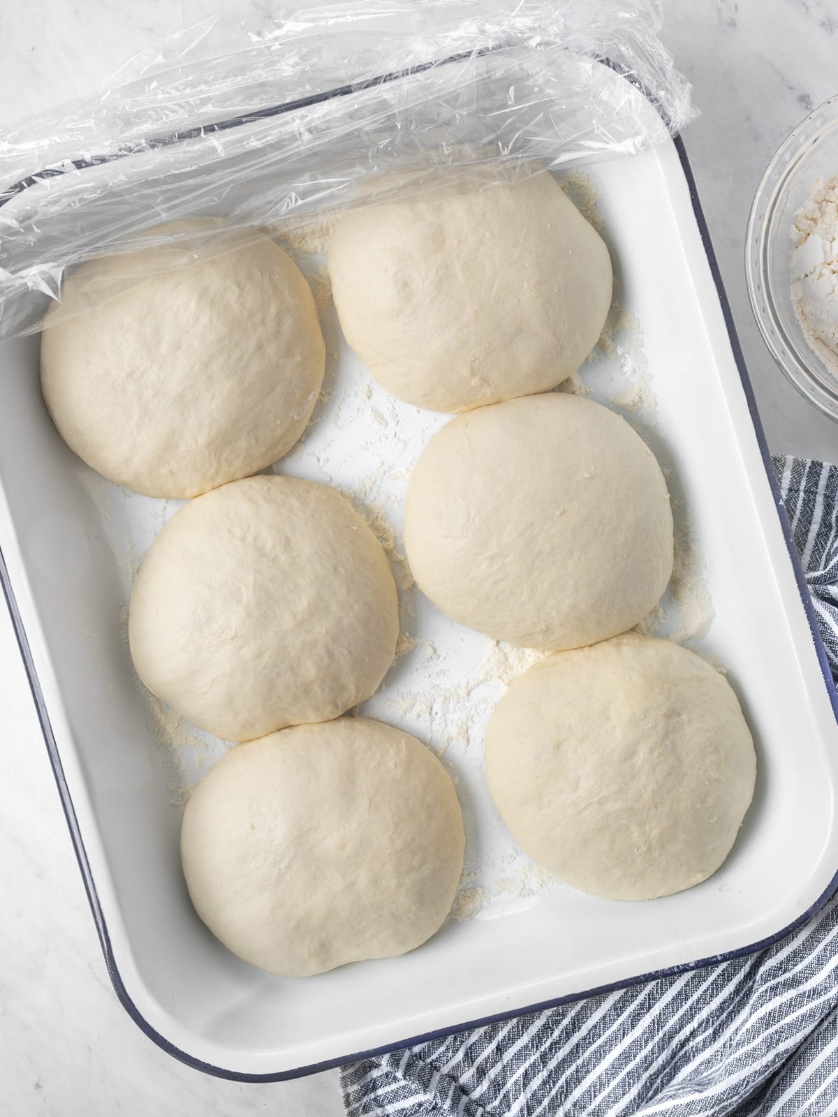 Proofing pan with 6 pizza dough balls.