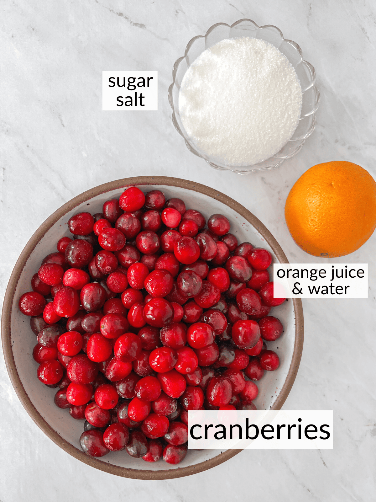 Bowl of cranberries, and orange and a bowl of sugar.