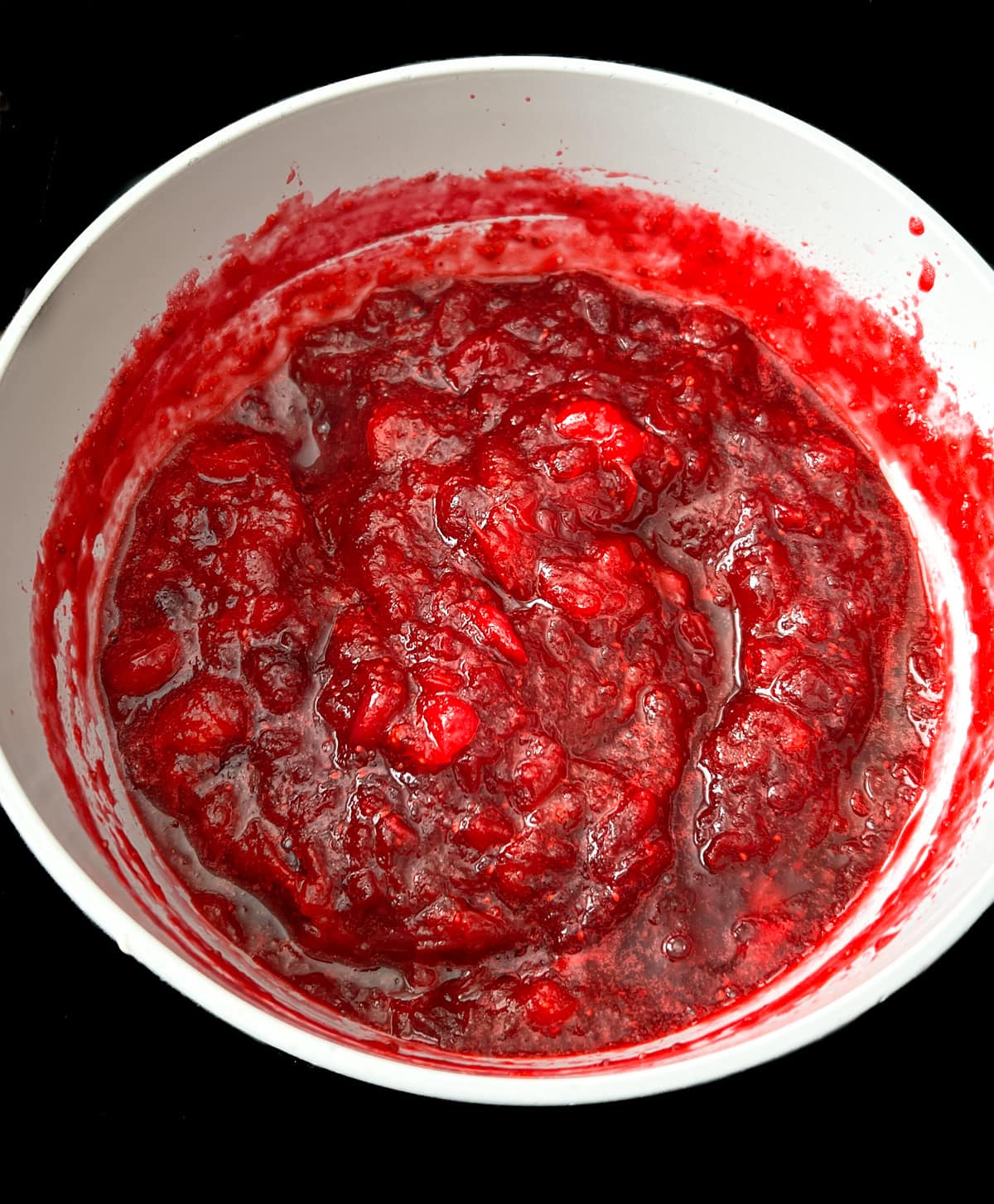 Cranberry sauce simmering in saucepan.