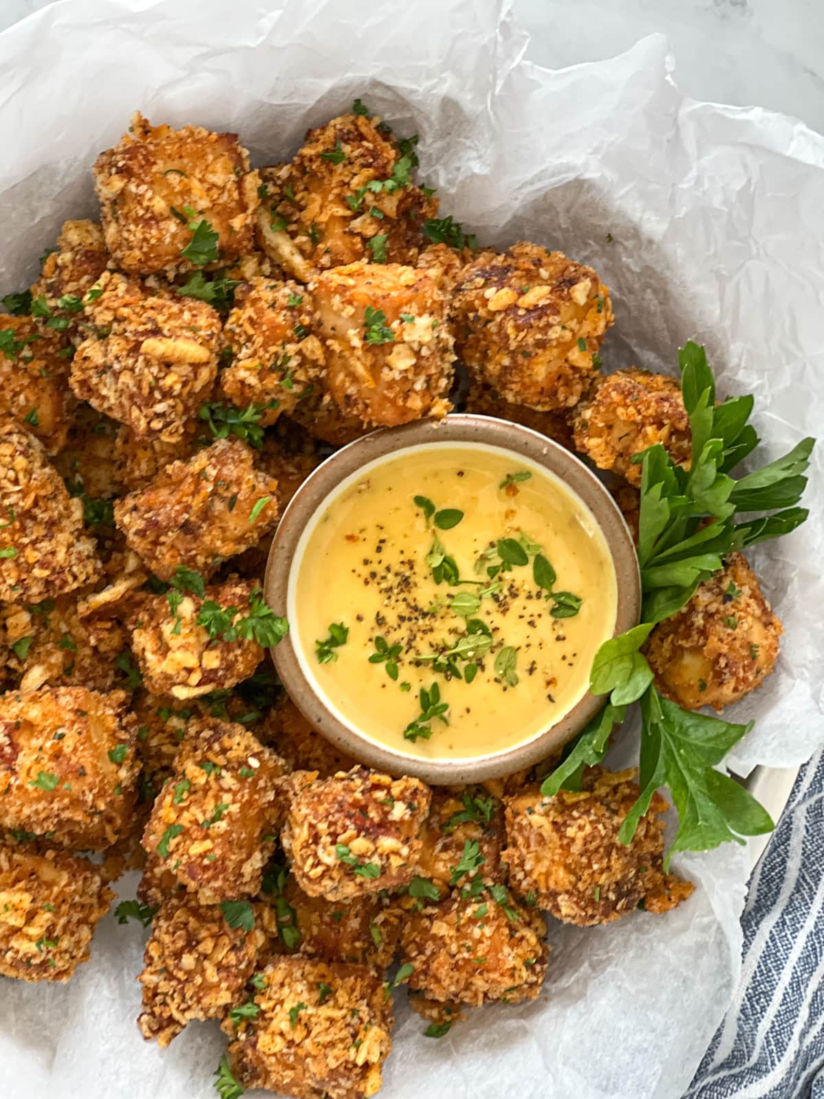 Bowlful of crunchy breaded tofu nuggets with a bowl of honey mustard sauce.