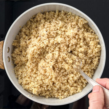 Quinoa in a pan being fluffed with a fork.