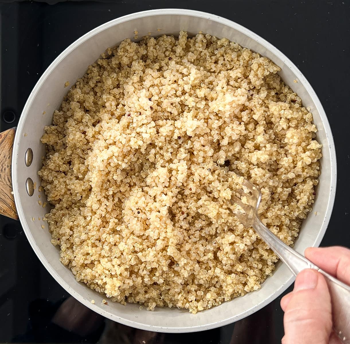 Quinoa in a pan being fluffed with a fork.