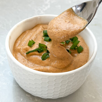 Bowlful of dairy free cashew queso with spoon.