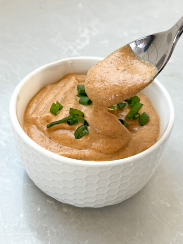 Bowlful of dairy free cashew queso with spoon.