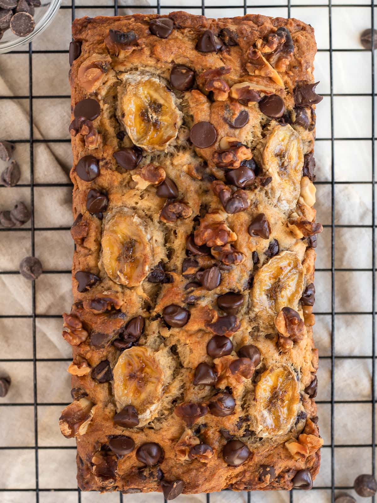 Banana bread with nuts and chocolate chips cooling on a wire rack.