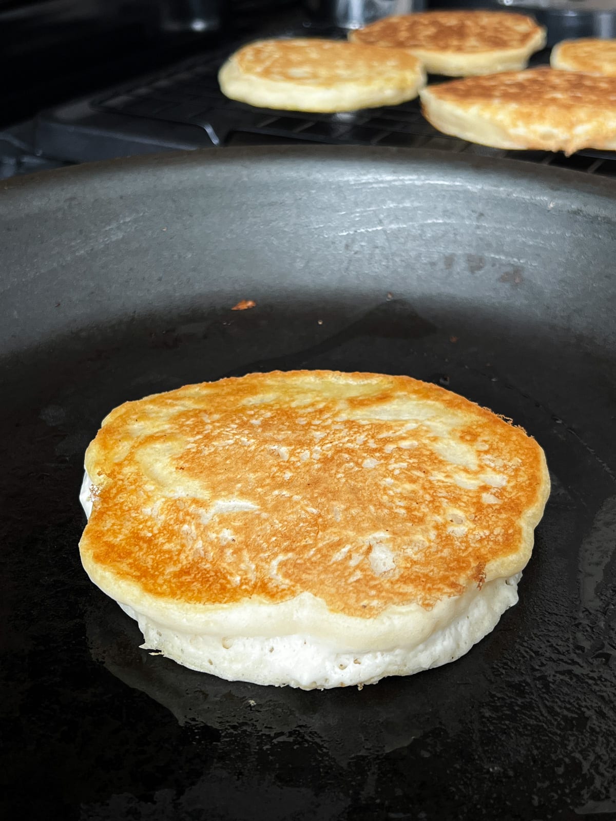 Fluffy tender buttermilk pancakes cooking on a hot skillet.