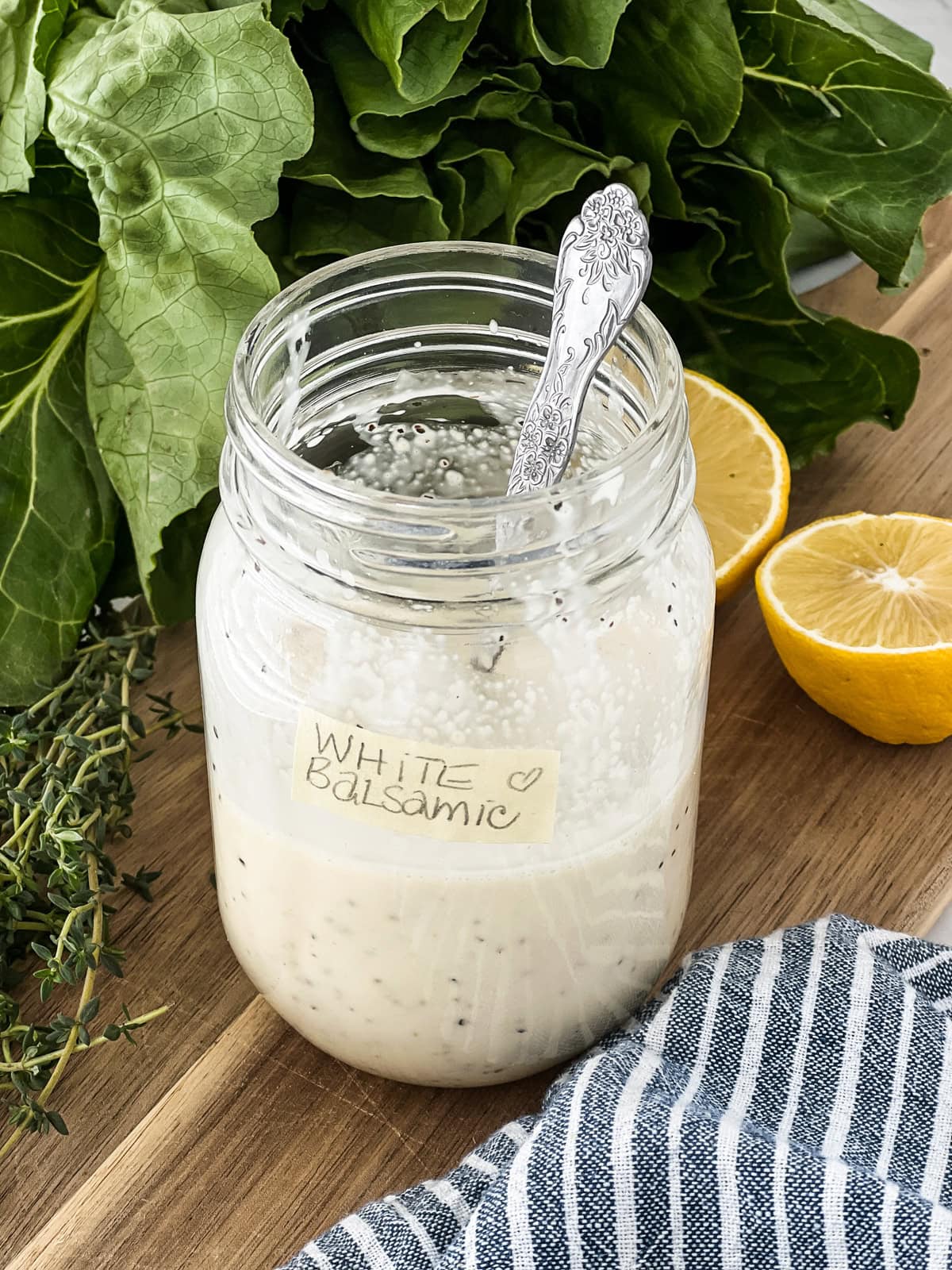 Jar of creamy white balsamic dressing with a spoon in it.