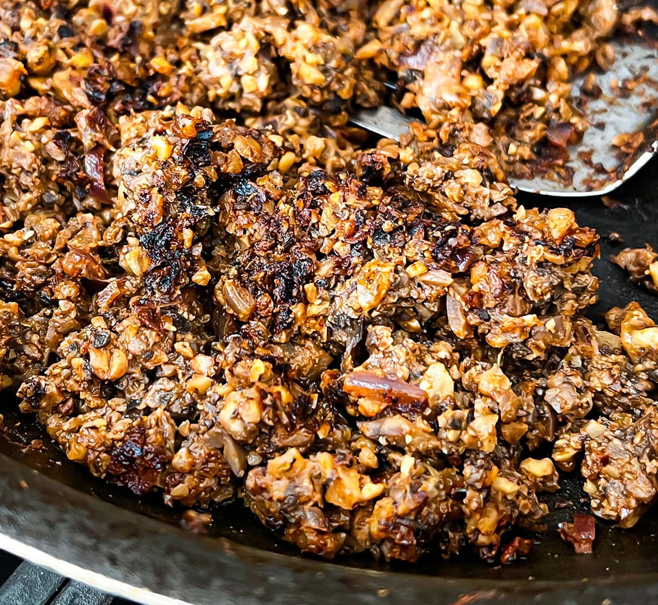 Juicy, charred ground mushroom walnut meat frying in skillet.