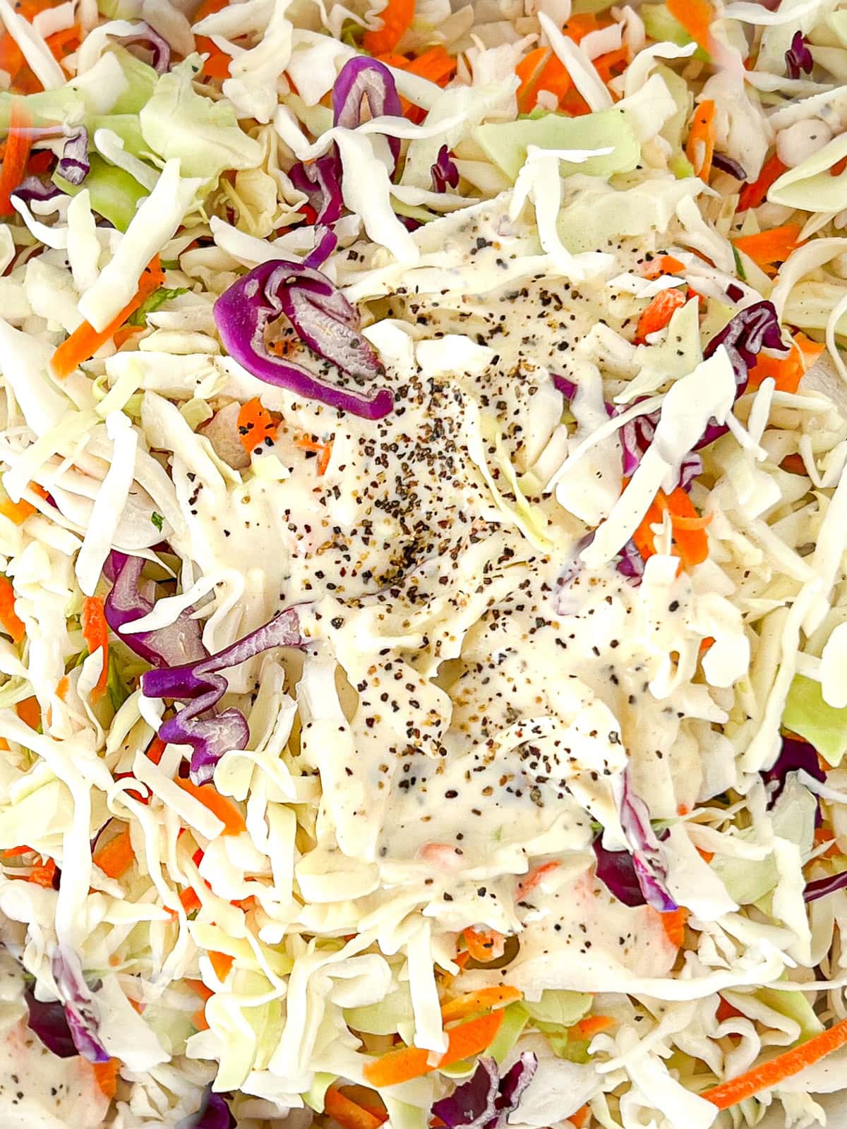 Vegan coleslaw with dressing in a bowl.
