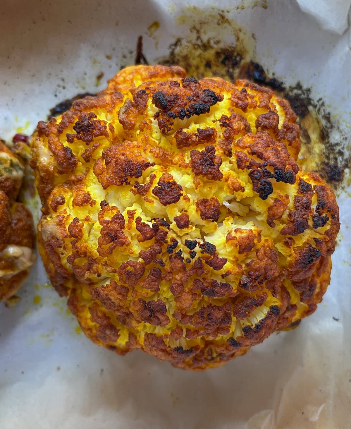 Roasted whole cauliflower on baking sheet.