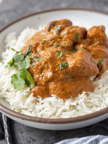 Baked tofu smothered in vegan butter chicken sauce on a bed of rice.