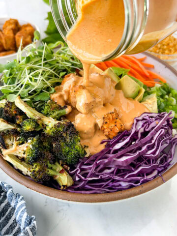 Thai peanut sauce being poured onto spicy peanut tofu bowls.